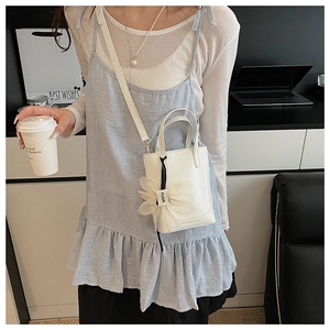 Detail of white mini bucket bag with tulle flower charm and adjustable shoulder strap