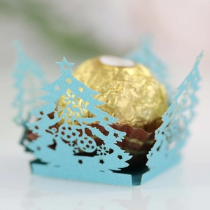 Macro view of light blue laser-cut Christmas tree chocolate wrapper with hollow details