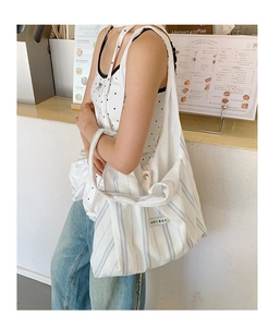 Detailed side view of a spacious blue and white striped canvas tote bag on person