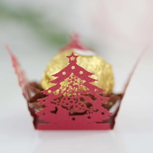 Detail of red laser-cut Christmas tree chocolate holder with star top and festive patterns