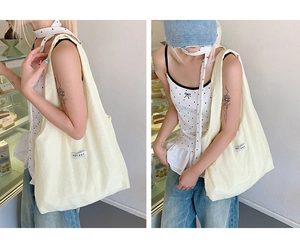 Detail of light yellow canvas tote bag with floral embroidery and corduroy texture