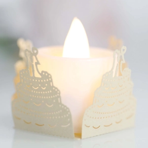 Macro detail of laser-cut wedding cake paper sleeve with warm LED tea light glow
