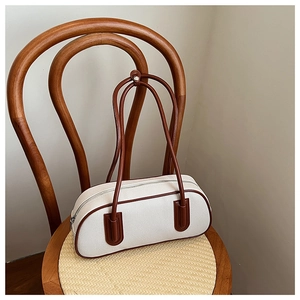 Close-up of retro canvas pillow bag with brown leather trim hanging on a wooden chair