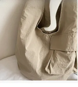 Detail of light khaki tote bag with natural pleated texture and side pocket design