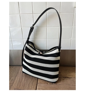 Détail d'un sac à bandoulière rayé en tricot avec fermoir en bois et sangle en cuir