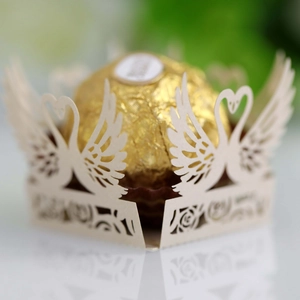 Macro detail of laser-cut swan chocolate wrapper with intricate ivory hollow patterns