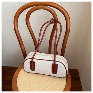 Dettaglio borsa bowling vintage in tela bianca con finiture in pelle marrone su sedia retro
