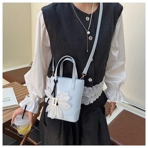 Detail of light blue mini bucket bag with a large white 3D flower and FUOR label