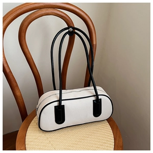 Detail of cream canvas bowling bag with black leather trim on a vintage chair