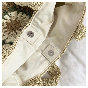 Detail of metal magnetic clasp closure and canvas lining on a colorful woven tote bag