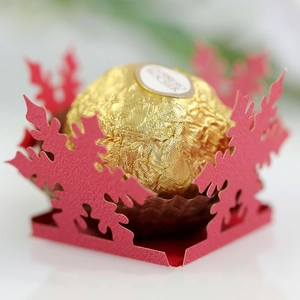 Detail of red laser-cut snowflake candy box with gold chocolate for Christmas party