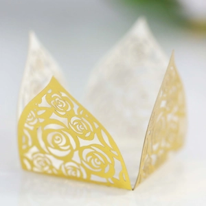 Macro shot of laser-cut gold paper cupcake liners with hollow rose floral patterns