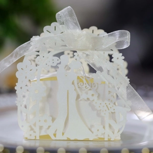 Macro shot of laser cut wedding candy box with bride and groom silhouette and ribbon