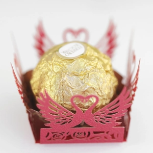 Macro detail of red laser-cut heart and swan lace paper wrapper for chocolate candy