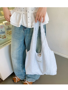 Close-up of a blue floral canvas tote bag featuring small white petal patterns and label