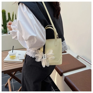 Detail of cream yellow mini bucket bag with tulle flower charm and fashion embossing