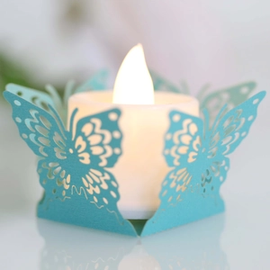 Détail de motif papillon découpé au laser sur papier sarcelle avec bougie LED chaleureuse