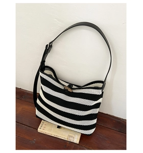 Detail of woven striped tote bag featuring leather strap and a bamboo toggle closure