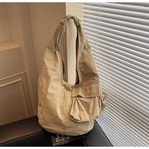 Detail of knot shoulder strap and crinkled texture on large beige nylon tote bag