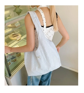 Shoulder view of light blue floral canvas tote bag with white small flower print