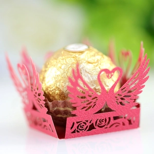 Close-up of a red laser-cut wedding favor box with swan design and chocolate inside