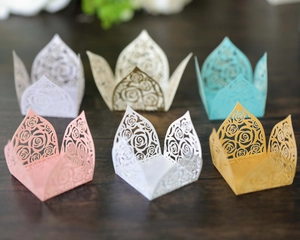 Detailed laser-cut rose patterns on paper cupcake wrappers in various pastel colors