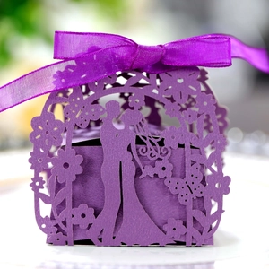 Close-up of purple laser-cut wedding favor box with romantic silhouette and ribbon