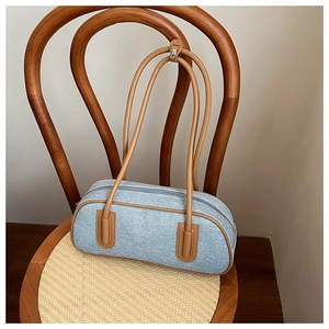 Dettaglio borsa a cuscino in denim blu con finiture in pelle marrone su sedia