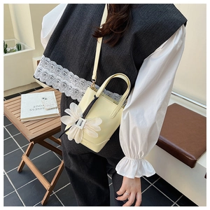 Detail of light yellow bucket bag with a large white silk flower charm and FUOR logo