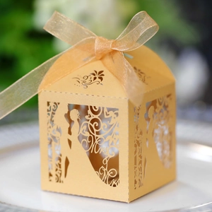 Detail of laser-cut gold wedding favor box with romantic silhouette and silk ribbon