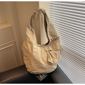 Detail showing knotted shoulder strap and textured fabric of beige tote bag