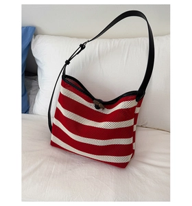 Detail of red and white striped knit hobo bag with black leather strap and wooden toggle