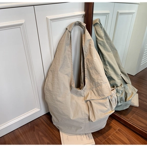 Detailed side view of beige large-capacity shoulder tote bag with functional flap pocket