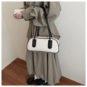 Dettaglio della borsa a spalla beige minimalista con bordo nero sulla modella