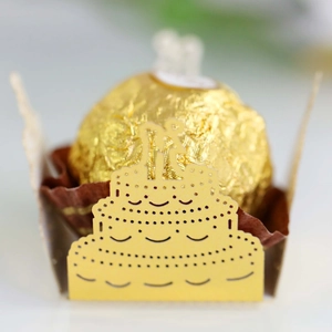 Macro detail of laser-cut yellow paper cake box featuring hollow wedding silhouette
