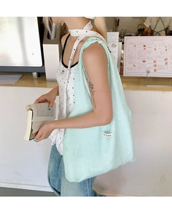 Detail of mint green floral canvas tote bag showing pleated texture and woven label