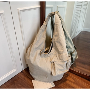 Detail view of large nylon tote bag featuring side flap pockets and wide shoulder straps