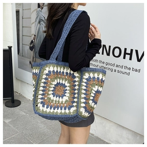 Detailed macro of the colorful handmade granny square crochet pattern on a woven tote bag