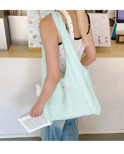 Detail of mint green floral canvas tote bag with lightweight fabric and side brand label