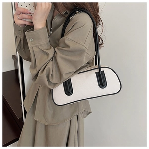 Detail of a minimalist beige and black contrast underarm bag styled with an elegant outfit