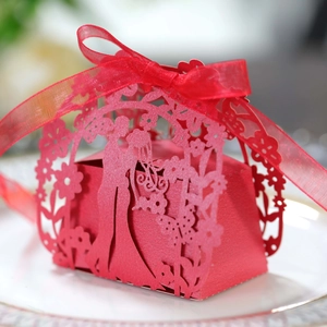 Detail of laser-cut wedding candy box with red ribbon and bride groom silhouettes