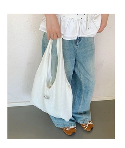 Close-up of white floral textured tote bag showing fabric details and brand label
