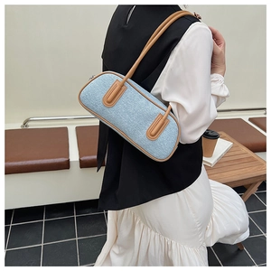 Borsa sottobraccio in denim blu con finiture in pelle marrone in un interno elegante