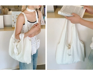 Close-up of white canvas tote bag with subtle dot texture and wide shoulder strap