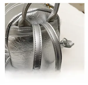 Close-up of silver crinkle textured backpack featuring reinforced stitching on straps