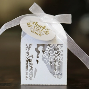 Detail of laser-cut wedding favors box with Mr & Mrs silhouette and white ribbon tie