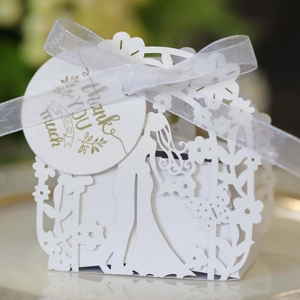 Close-up of white laser-cut wedding favor box with bride silhouette and silk ribbon