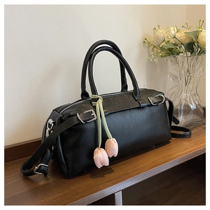 Detail of black lychee grain leather Boston bag with pink tulip charms and silver hardware