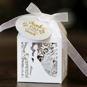 Macro detail of white laser-cut wedding favor box with Mr & Mrs text and thank you tag