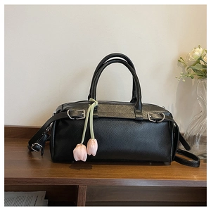 Detail of black lychee grain leather bag with silver buckles and a pink tulip charm